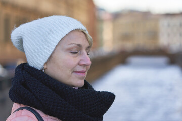 Portrait of a middle aged woman with closed eyes in a scarf and hat
