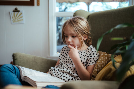 Young girl reading a book at home