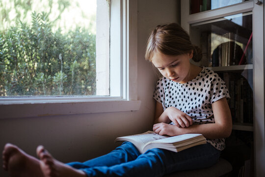 Young girl reading a book at home