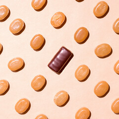 Pattern of caramel and chocolate candies on a beige background. View from above