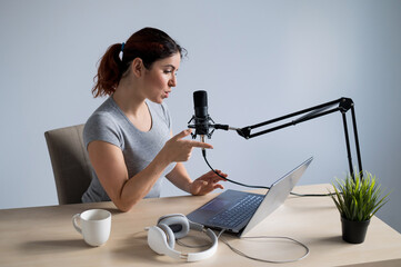 A charming woman radio host is broadcasting live on a laptop. Online radio concept