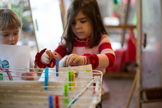 Child hanging a painting with pegs