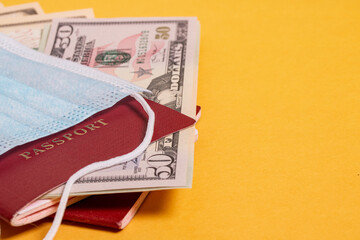 The coronavirus pandemic. Medical mask, passport, money on an orange background.Risk of cancellation of international travel due to COVID-19. The concept of virus spread syndrome.