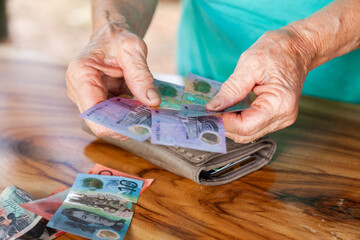 Old persons hands handing over australian bank notes