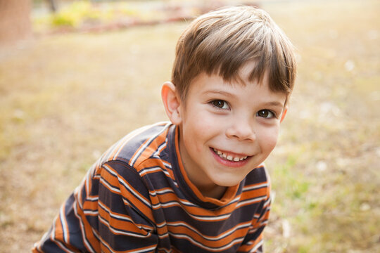 Portrait of happy young boy smiling at camera outdoors