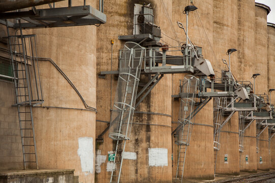 Wheat silo infrastructure beside a train line on an overcast day