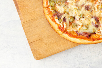 Rustic pizza with salami, mozzarella, cucumbers and chiken top view. copy space.