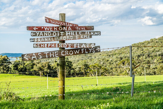 A post with hand painted signs showing directions to local towns