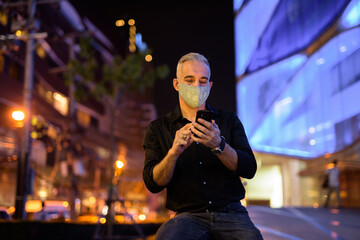 Man at night on the streets wearing protective facial mask to protect from covid 19 corona virus...
