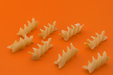 Fusilli macaroni Italian dry raw pasta bronze drawn, rough paste from Gragnano,Naples,Italy, close up on orange background