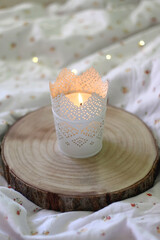 Wooden tray with candle holder and lit candle. Selective focus, bokeh lights.