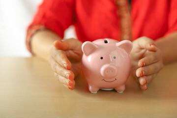 Portrait of Indian woman holding piggy bank for savings	
