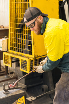 A tradesman wearing high vis clothing bending steel on pegs in an anvil