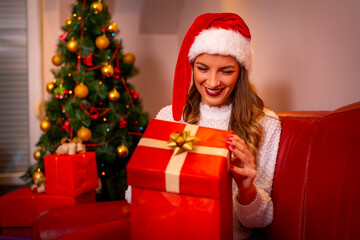 Fototapeta na wymiar Smiling young woman with christmas present box near christmas tree