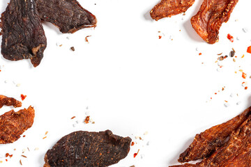 Chicken and beef jerky with spices on a white background top view. Free space for text. Tasty spicy jerky, homemade beer snack. - obrazy, fototapety, plakaty