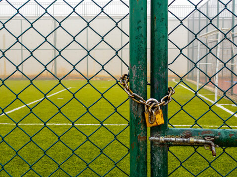 closed and locked football field with green wire netting.