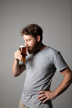 Young man sitting, holding a glass of beer, relaxed and happy
