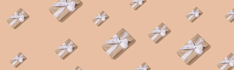 New Year's composition. Trendy New Year pattern of gift boxes in paper with a white ribbon with a hard shadow on a sand-colored background. Flat lay, top view. Creative minimal christmas art.