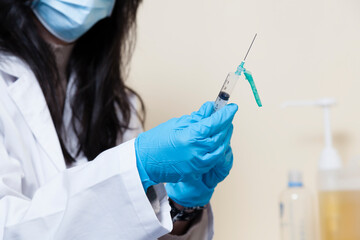 Female researcher manipulating syringe on a clinic environmenrt.