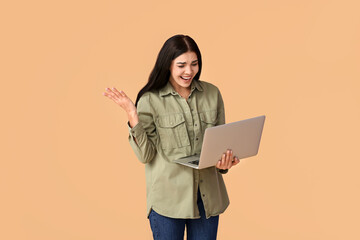 Stressed young woman with laptop on color background
