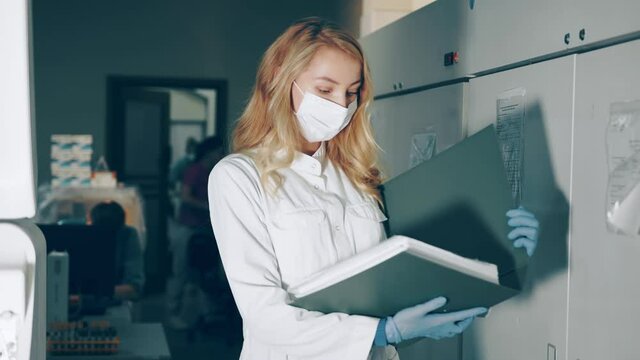 Portrait of a lab worker with a research folder in her hands. Ladorant reviews research records in the journal. Laboratory for the study of biochemical infections of the virus in the blood.
