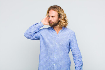 blonde man looking serious and curious, listening, trying to hear a secret conversation or gossip,...
