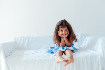 Obraz na płótnie Canvas Portrait of a beautiful little curly girl in a blue dress