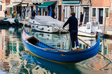 Fototapeta na wymiar Gondoliere naviga in un canale di Venezia