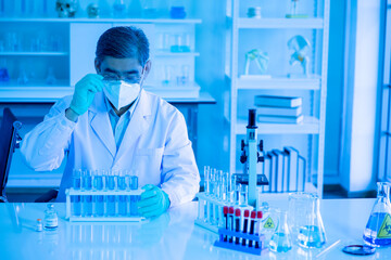 Asian medical doctor scientists in lab gown and face protective mask working with microscope and test tubes in clinical laboratory. virus pandemic concept. healthcare and medicine concept. 