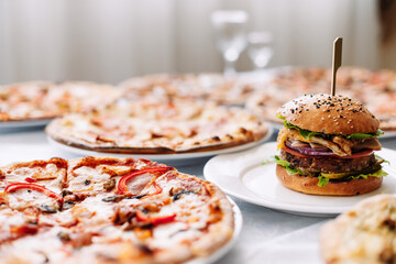 Assorted different pizzas and burgers on the table for tasting or working out the menu, side view