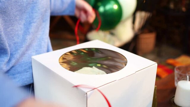 women's hands unpack a box with a birthday cake. desserts to order for your birthday.