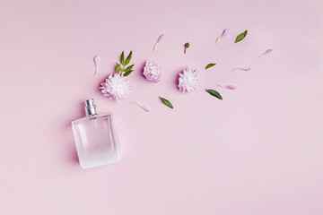 A bottle of perfume, flowers and petals on pink background.