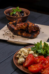 Food set with grilled pork ribs, pickled vegetables, bacon, salad, and moonshine  on black wooden background