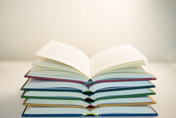 Opened colorful books stacked on a table, with white background