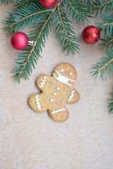 Christmas composition. Gingerbread man in a medical mask on a wooden background with red balls and a green Christmas tree.