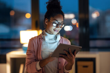 Beautiful young entrepreneur woman using her digital tablet standing in the office.