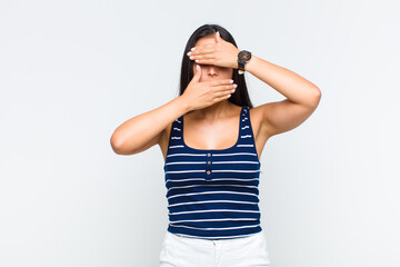 young woman covering face with both hands saying no to the camera! refusing pictures or forbidding...