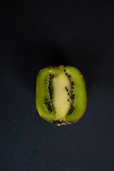 half a fresh kiwi in water on a black background with air bubbles