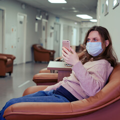 Obraz premium A patient in the clinic corridor is watching an appointment with a doctor online on their phone