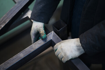 Photo of a welder's hand working measures metal in a workshop