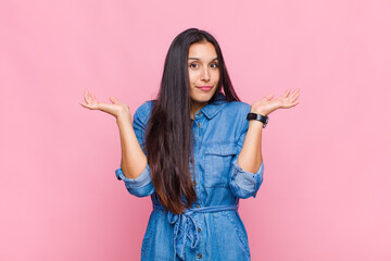 young woman feeling puzzled and confused, doubting, weighting or choosing different options with...