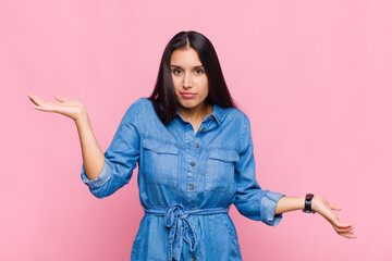 young woman looking puzzled, confused and stressed, wondering between different options, feeling...