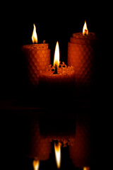 Close-up of three small yellow candles on a black background.