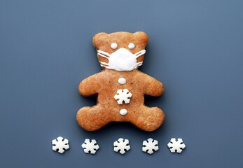 Gingerbread bear with protective face mask and small sugar snowflakes. Christmas or New year concept. Coronavirus winter