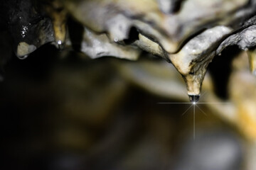 Hanging drop on a stalactite formation in a cave