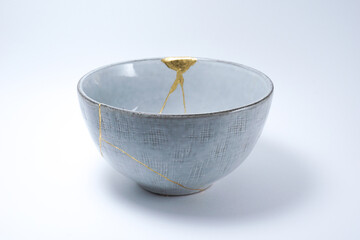 Kintsugi Japanese grey bowl. Gold cracks restoration on pottery restored with the antique Kintsugi restoration technique. The beauty of imperfections. representation of trauma. 