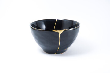Black kintsugi bowl. Gold cracks restoration on pottery restored with the antique Kintsugi restoration technique. The beauty of imperfections. representation of trauma. 