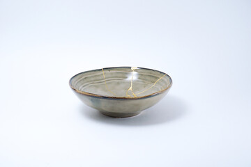 Beige kintsugi bowl. Gold cracks restoration on pottery restored with the antique Kintsugi restoration technique. The beauty of imperfections. representation of trauma.