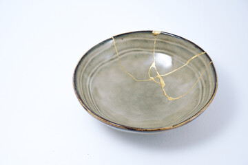 Beige kintsugi bowl. Gold cracks restoration on pottery restored with the antique Kintsugi restoration technique. The beauty of imperfections. representation of trauma.