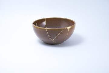 Brown kintsugi bowl. Gold cracks restoration on pottery restored with the antique Kintsugi restoration technique. The beauty of imperfections. representation of trauma. 